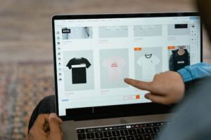 A dropshipper working from home pointing to a t-shirt design on their computer.
